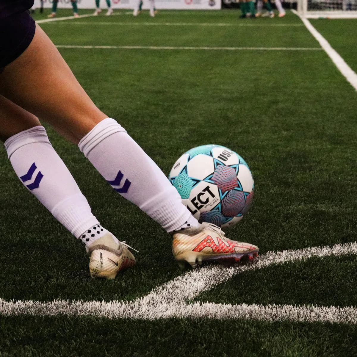 Primer plano de un futbolista ejecutando un córner junto a la línea de esquina