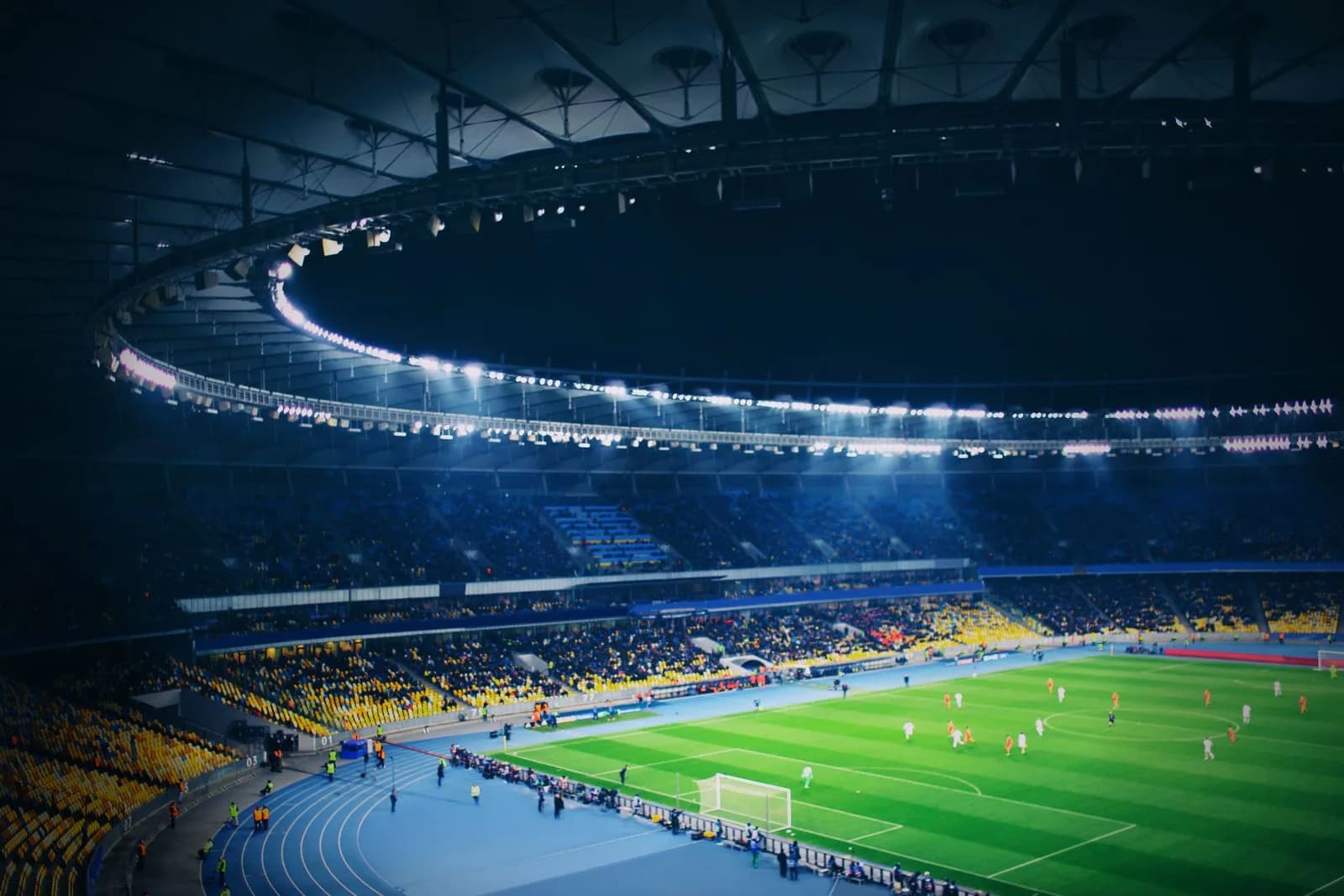 Partido de fútbol visto desde la tribuna de un estadio iluminado